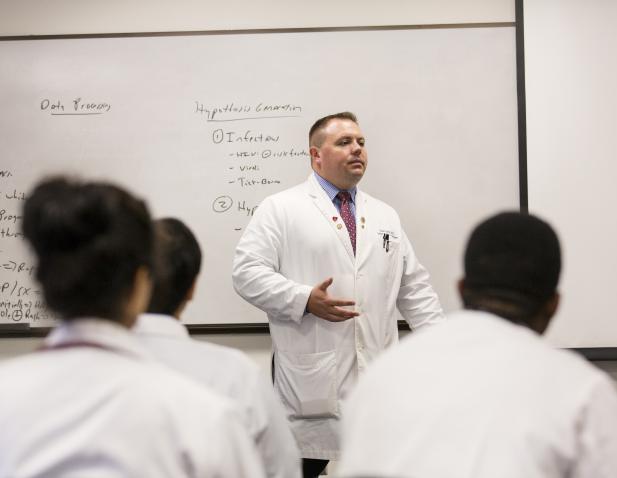 Dr Gable lectures to residents in front of white board.