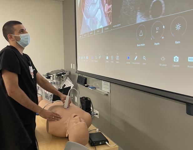 Medical resident performs ultrasound in simulation lab on mannequin.