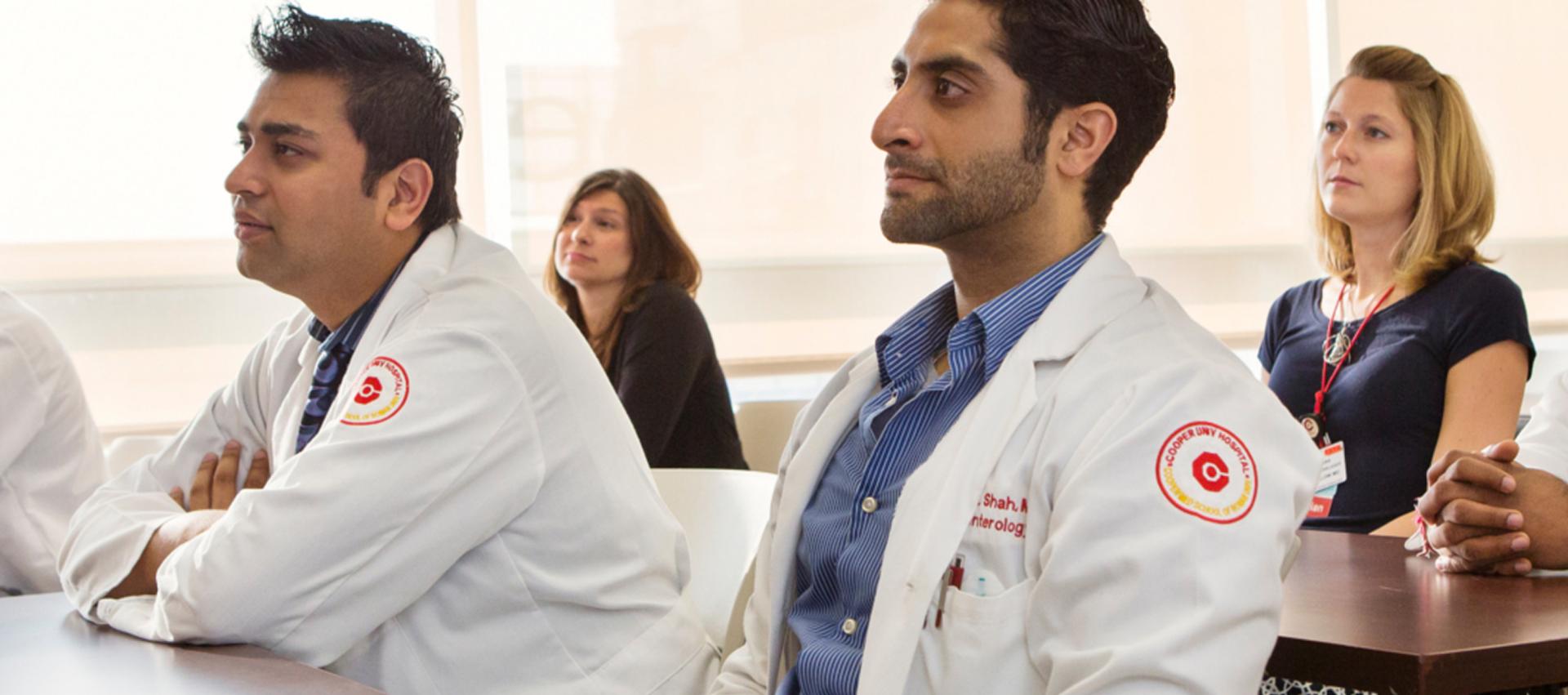 Medical residents and students attentively listening during a classroom lecture at Cooper University Health Care.
